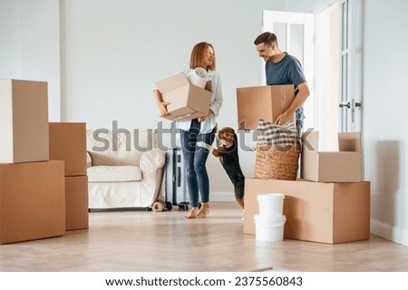 Two boxes in hands. Young couple with dog are moving to new home.