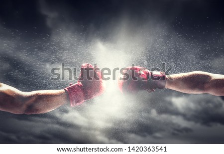 Two boxing gloves punch. Light on cloudy sky. Box, power, fight symbols.