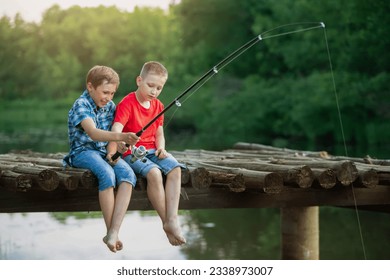 Two boy friends are sitting on a wooden bridge and fishing. Children on a fishing trip. - Powered by Shutterstock