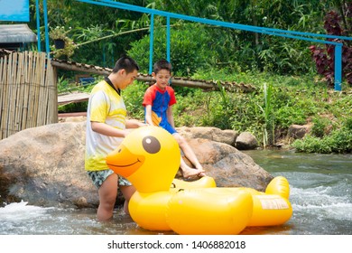 Two boy prepare to jump on plastic duck balloon to row downstream  - Powered by Shutterstock