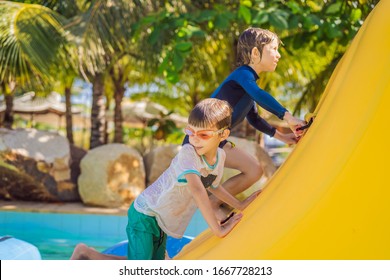 Two boy runs an inflatable obstacle course in the pool