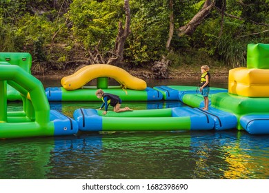 Two Boy Runs An Inflatable Obstacle Course In The Lake