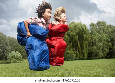 Two Boys (7-9) Racing In Sleeping Bags