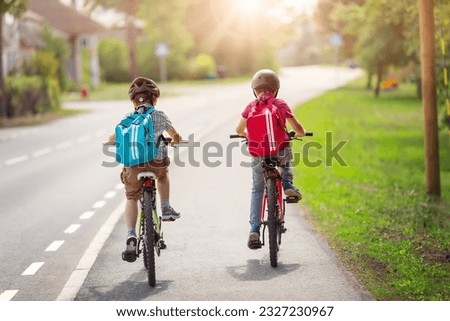 Two boys with backpacks on bicycles going to school.