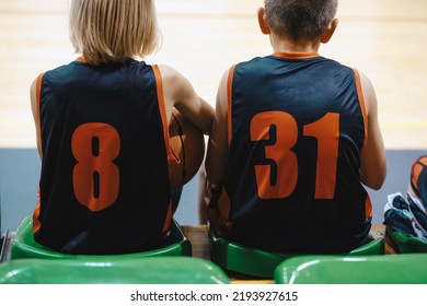 Two Boys In Basketball Team Sitting On Substitute Players Bench. Children Play Basketball Game. Youth Basketball Background. Sports Education