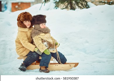 Two boys brother enjoy a sleigh ride. Child sledding. Toddler kid riding a sledge. Children play outdoors in snow. Kids sled in winter.  Little rabbits in the hands. 