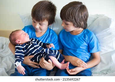 Two Boys, Brothers, Meeting For The First Time Their New Baby Brother At Hospital. Family Happiness Concept