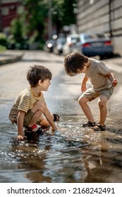 deux garçons, deux frères qui jouent dans une flaque. Des enfants heureux marchent dehors après la pluie par une chaude journée d'été ensoleillée