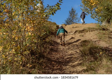 Two Boys Climbing Up The Hill In Autumn Park
