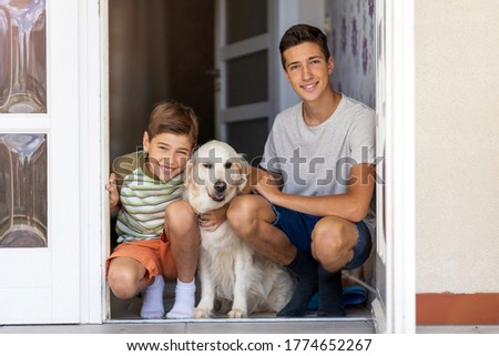 Two boys with a dog in doorway of their house
