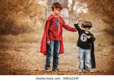 Two Boys Dressed As Superheroes Compare Their Power In The Playground Summer Day