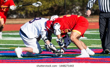 Two Boys Fight For The Ball During The Faceoff Of A High School Lacrosse Game.