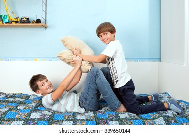 a two boys is fighting by pillows in bedroom