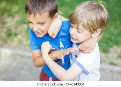 Two boys fighting outdoors. Friends wrestling in summer park. Siblings rivalry.