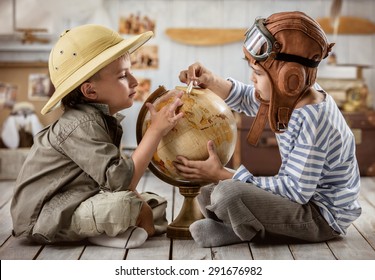 Two boys in the form of pilot and tourists planning on a globe of their travel route - Powered by Shutterstock