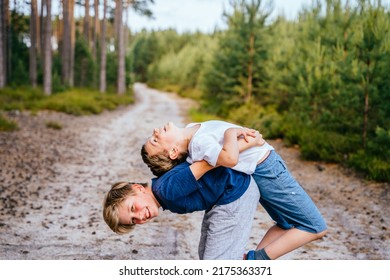 Two boys, friendsor brothers wrestle, compete, play active games in the pine forest on vacation. - Powered by Shutterstock