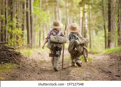 Two boys go hiking with backpacks on a forest road bright sunny day - Shutterstock ID 197127548