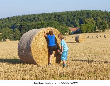 Two Boys Helping Each Other to Climb a Bale of Hay
