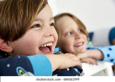 Two Boys Leaning On The Top Of A Bunk Bed

