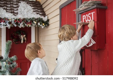 Two Boys Making Wishes And Putting Christmas Letters Into Red Post Box For Santa Claus 