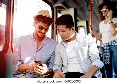 Two Boys On The Bus Looking At Phone.