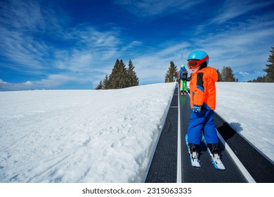 Two boys on the ski moving walkway belt at skiing school during winter vacations view from behind