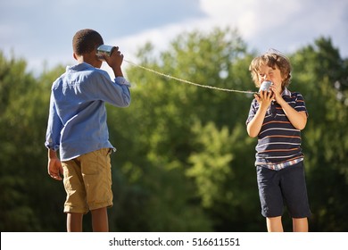 Two boys play tin can telephone in the summer