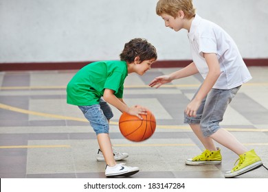 Two boys playing basketball together in the schoolyard of a school