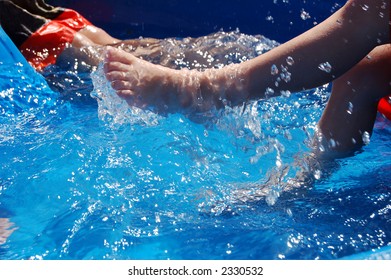 Two Boys Playing And Kicking In A Kiddie Pool.