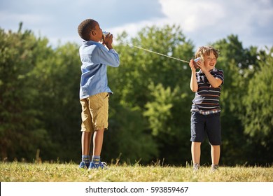 Two boys playing tin can telephone at the park
