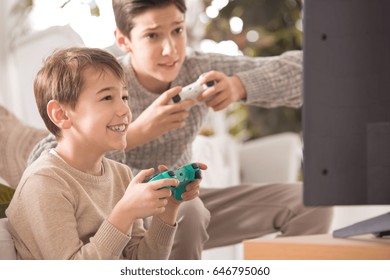 Two Boys Playing A Video Game On Playstation At Family Dinner