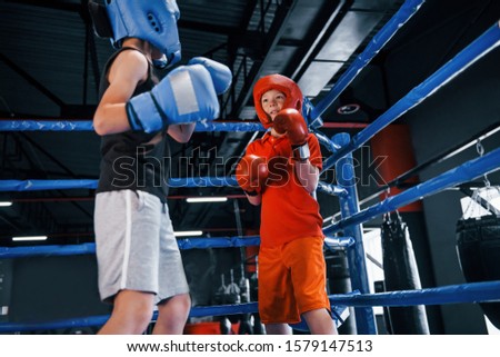 Two boys in protective equipment have sparring and fighting on the boxing ring.