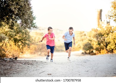 Two Boys Running And Racing Each Other Outdoors In Nature. Siblings Connection.