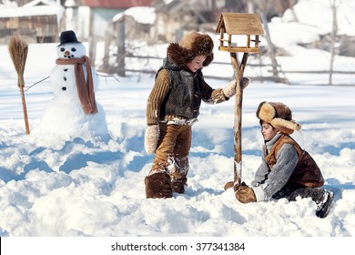 Two Boys Set The Bird Feeder In The Backyard Of The House A Winter Day