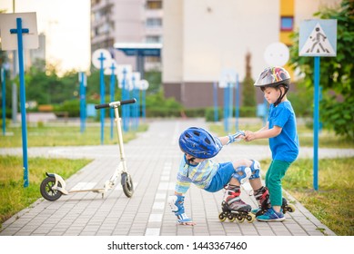 Two boys sibling brothers together in park, helps boy with roller skates to stand up after fall. Friendship and active leisure summer holidays time with family concept. - Powered by Shutterstock