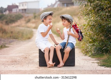 Two Boys, Sitting On A Big Old Vintage Suitcase, Eating Marshmallows And Talking