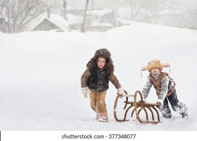 Two Boys Sledding With Mountain Warm Winter Day