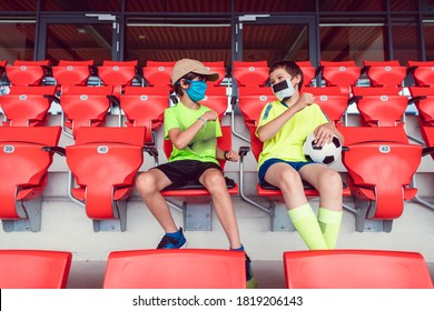 Two Boys In A Soccer Stadium Watching The Game During Covid-19 Wearing Face Masks