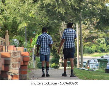 Two Boys Walking In Neighborhood Matching Paid Shirts