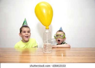 Two boys watching a chemistry experiment. children are surprised. Chemical reaction. the balloon is blow up when soda is added to a bottle of vinegar