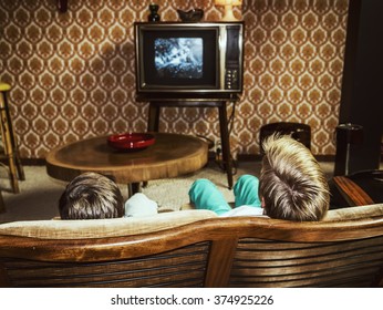 two boys watching television at home in 50's style, shot from behind