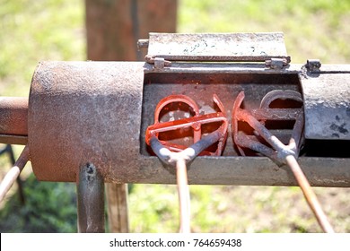 Two Branding Irons Heating In A Burner In A Field Glowing Red Hot Ready To Be Applied To Livestock