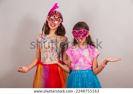 two Brazilian children, girls, dressed in carnival clothes, with open arms, welcome.