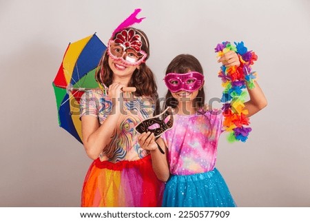 two Brazilian children, girls, dressed in carnival outfit, holding carnival accessories.