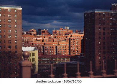 Two Bridges neighborhood. Roof tops of historic apartments in New York. High-rise and walk-up buildings under autumn stormy sky. Red brick walls with rows of windows in Lower East Side.