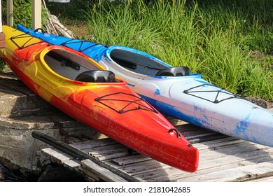 Two Bright Coloured Kayaks On Wooden Ramp At Cottage