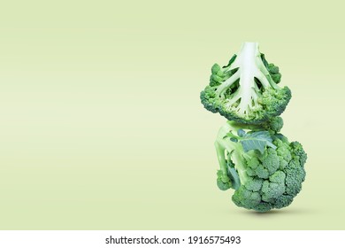 The two broccoli heads are stacked vertically. Equilibrium floating vegetables. Monochrome minimalistic composition. Balancing veggies. Copy space.