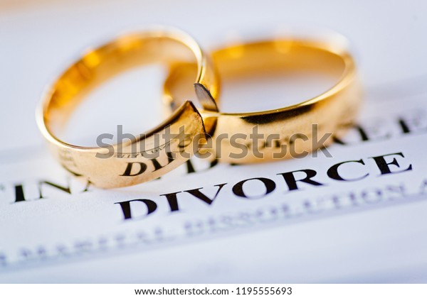Two broken golden wedding rings
divorce decree document. Divorce and separation
concept