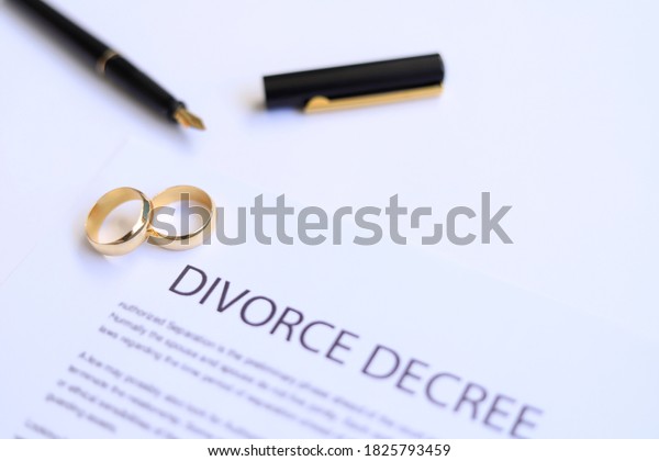 Two broken golden wedding rings\
divorce decree document. Divorce and separation concept.\
