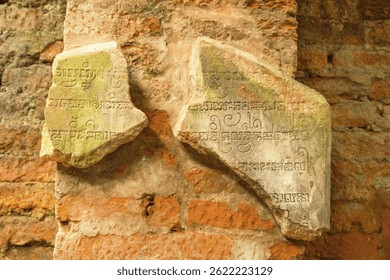 Two Broken Stone Tablets with Ancient Writings Displayed on a Weathered Brick Wall. My Son, Vietnam.